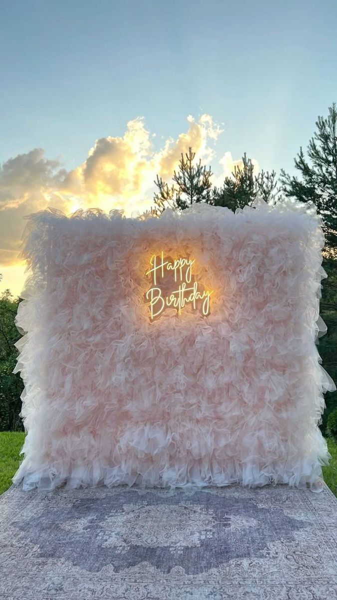Pared de tul rosa con letrero de neón Happy Birthday al atardecer